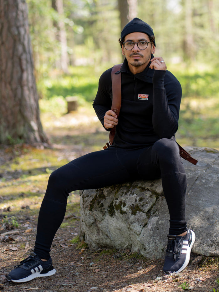 Ruskovillan musta merinovilla kerrasto ja pipo miehen päällä ulkona kesäisessä luonnossa